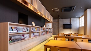 A library with wooden bookshelves, tables, and chairs. - Y's Cabin & Hotel Naha Kokusai Dori (Naha)