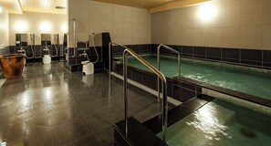 Een moderne spa met een ruime jacuzzi, een aparte douche en een zitbank.