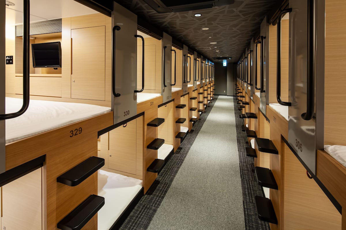 Vagón de tren con cabinas individuales para dormir, numeradas del 329 al 336, equipadas con camas y compartimentos para guardar objetos.
