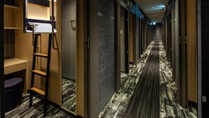 A hotel hallway with a carpeted floor, wooden doors, and a ladder in a room. - Y's Cabin & Hotel Naha Kokusai Dori (Naha)