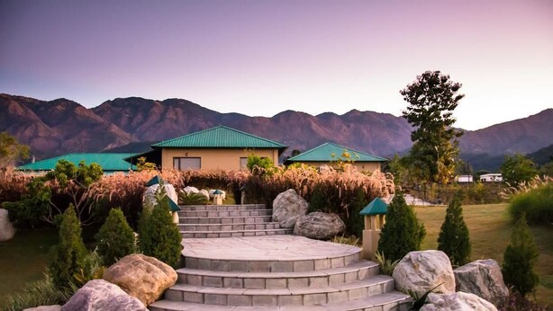 A two-story building with a green roof, surrounded by a landscaped garden with steps leading to the entrance. - Corbett The Baagh Spa & Resort (Ramnagar)