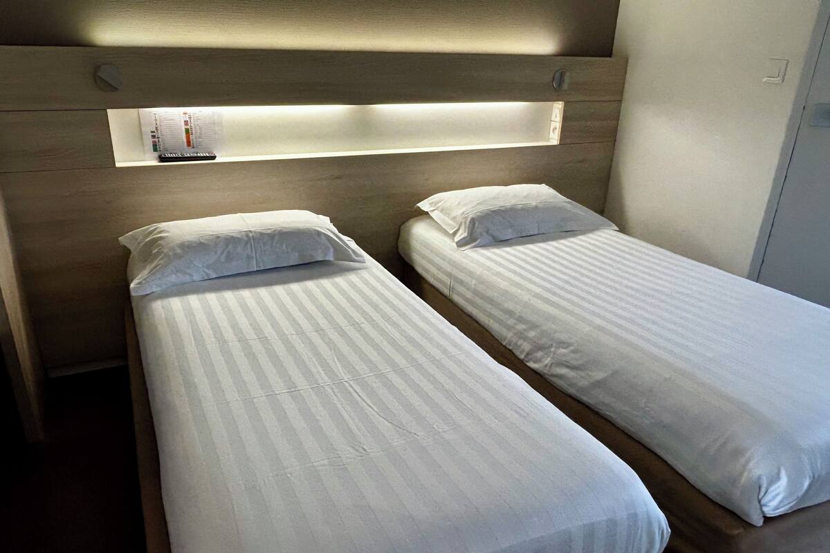 Una cama doble con ropa de cama blanca y un cabecero con iluminación integrada.