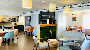 A modern cafe with a bar area, seating arrangements, and a decorative wall. - Hôtel Restaurant L’Eskemm *** St Brieuc-Trégueux (Tregueux)