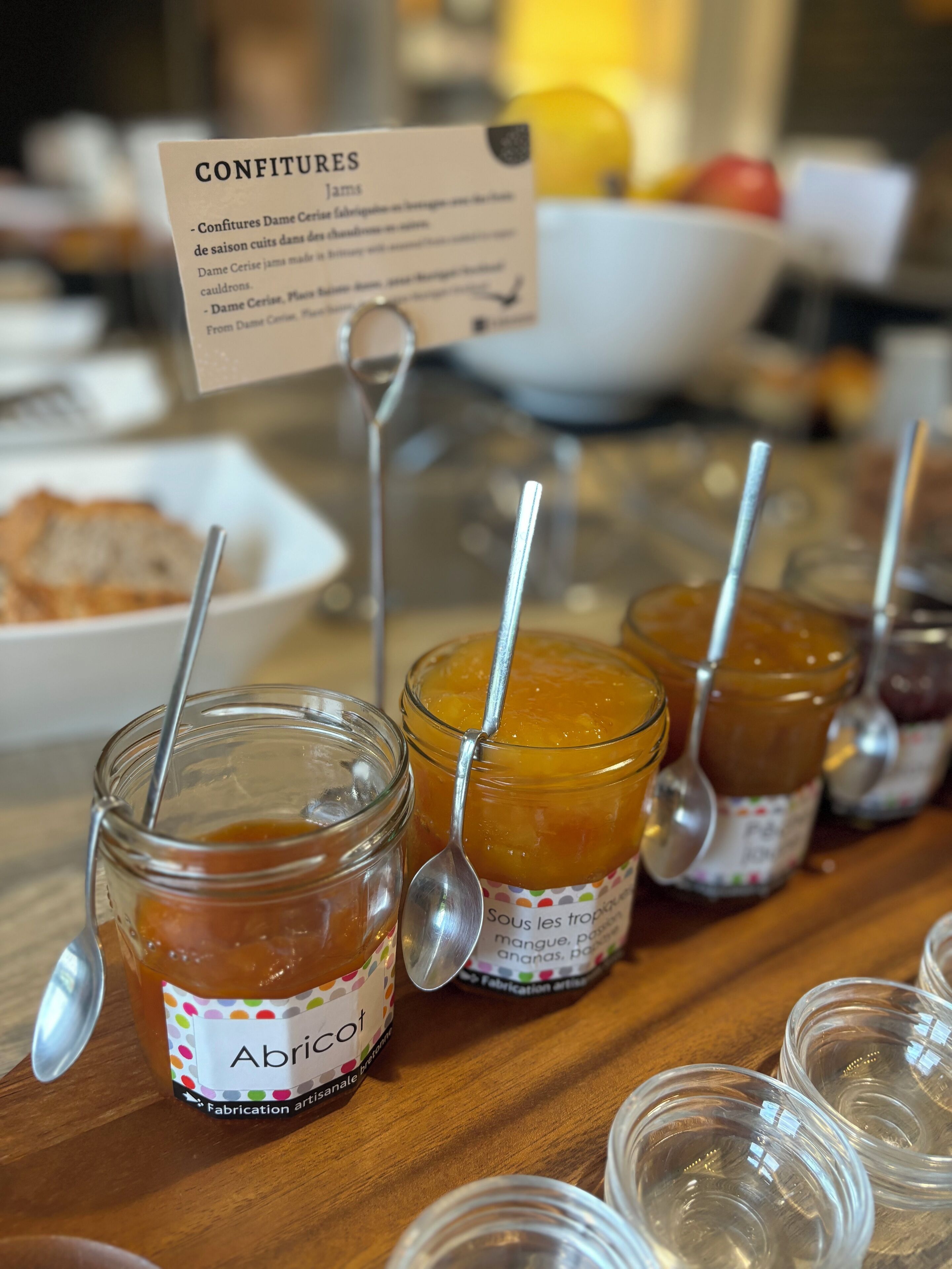A table with jars of jam labeled 'Abricot' and a sign reading 'CONFITURES'.