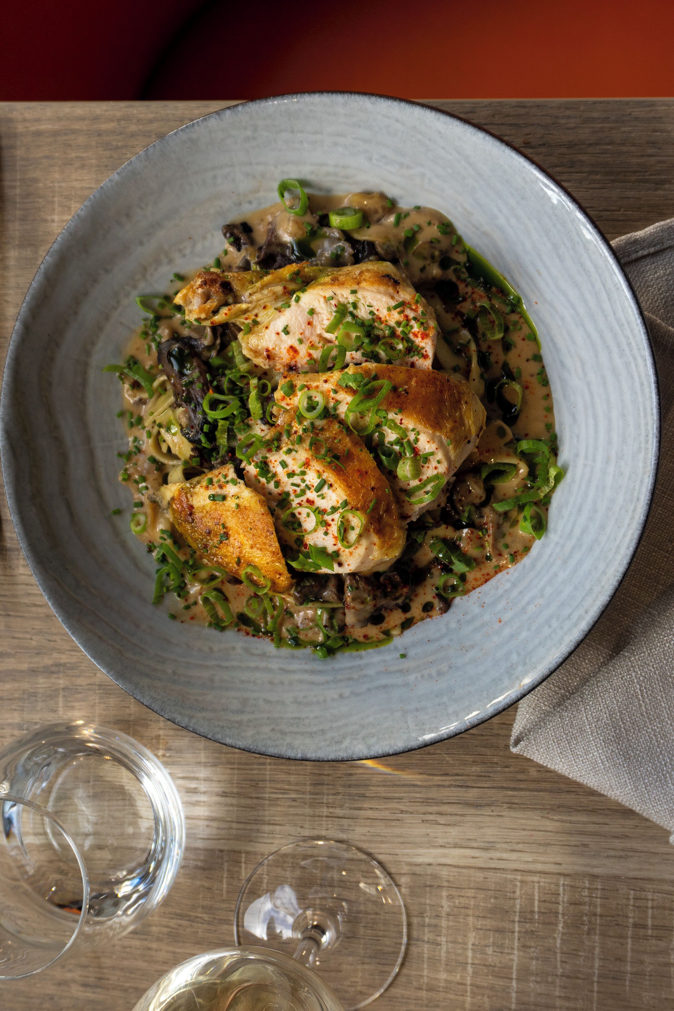 Een bord eten met een romige saus, groene bieslook en champignons.