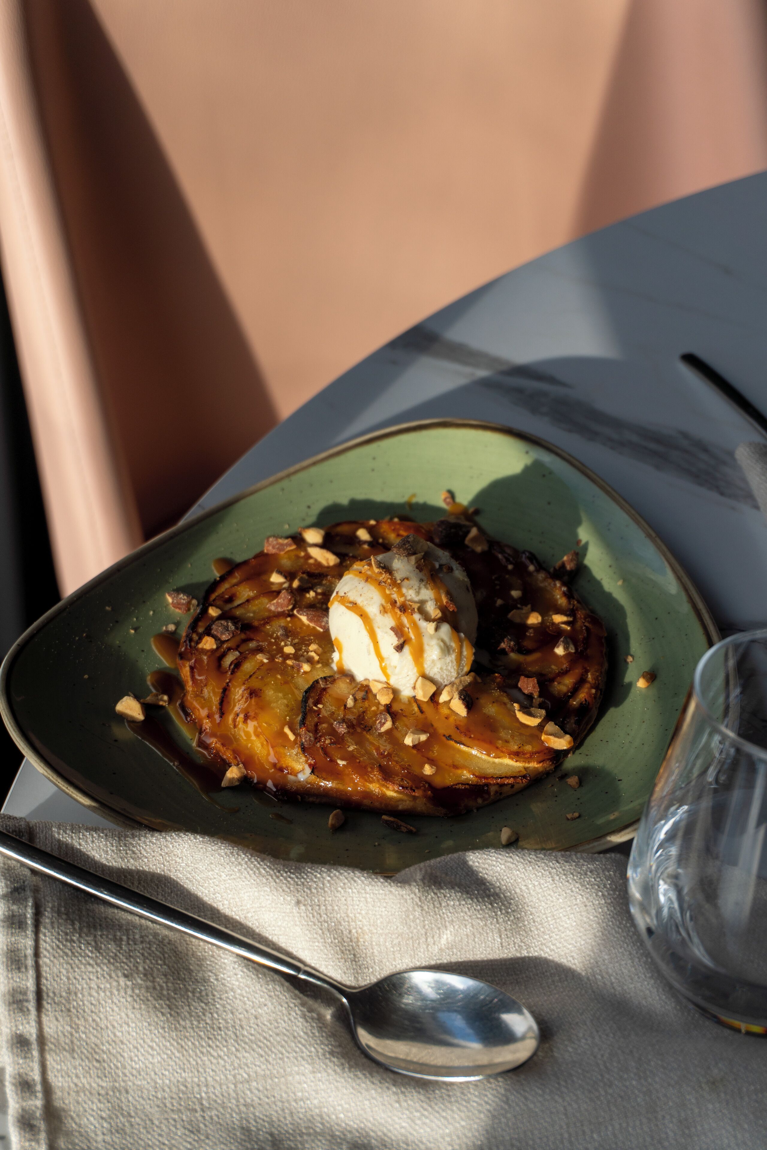 Postre a un plat amb una cullera i un got sobre una taula.