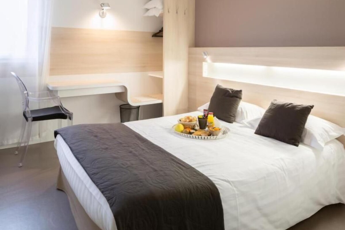Ein Hotelzimmer mit Bett, Schreibtisch und Stuhl.