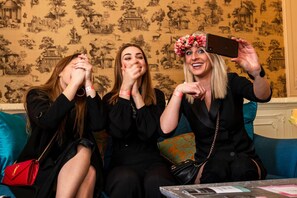 Tres personas sentadas en un sofá azul con un fondo de papel tapiz estampado.