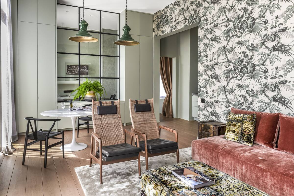 A modern living room with a red sofa, two armchairs, a coffee table, and a dining area with a white table and chairs.