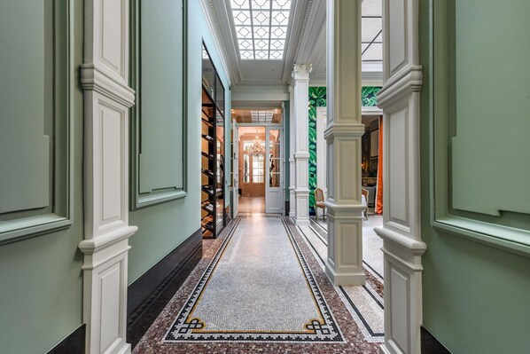 Un pasillo con alfombra estampada, columnas blancas y tragaluces.