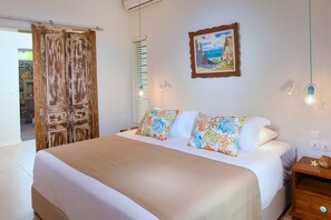 A bedroom with a bed, a wooden door, a painting, and a nightstand. - Beach and Pool Poste Lafayette (Poste Lafayette)