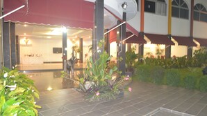 A hotel lobby with a tiled floor, potted plants, and a reception area with a counter and chairs. - Le Jardin d'eden 2 (Abidjan)