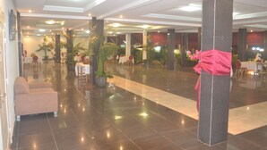 A spacious lobby with a polished floor, seating areas, and potted plants. - Le Jardin d'eden 2 (Abidjan)