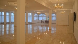 A spacious room with polished floors, large windows, and chandeliers. - Le Jardin d'eden 2 (Abidjan)