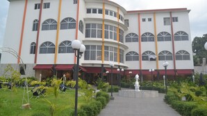 A multi-story hotel with a curved facade, large windows, and a central courtyard with seating and a fountain. - Le Jardin d'eden 2 (Abidjan)