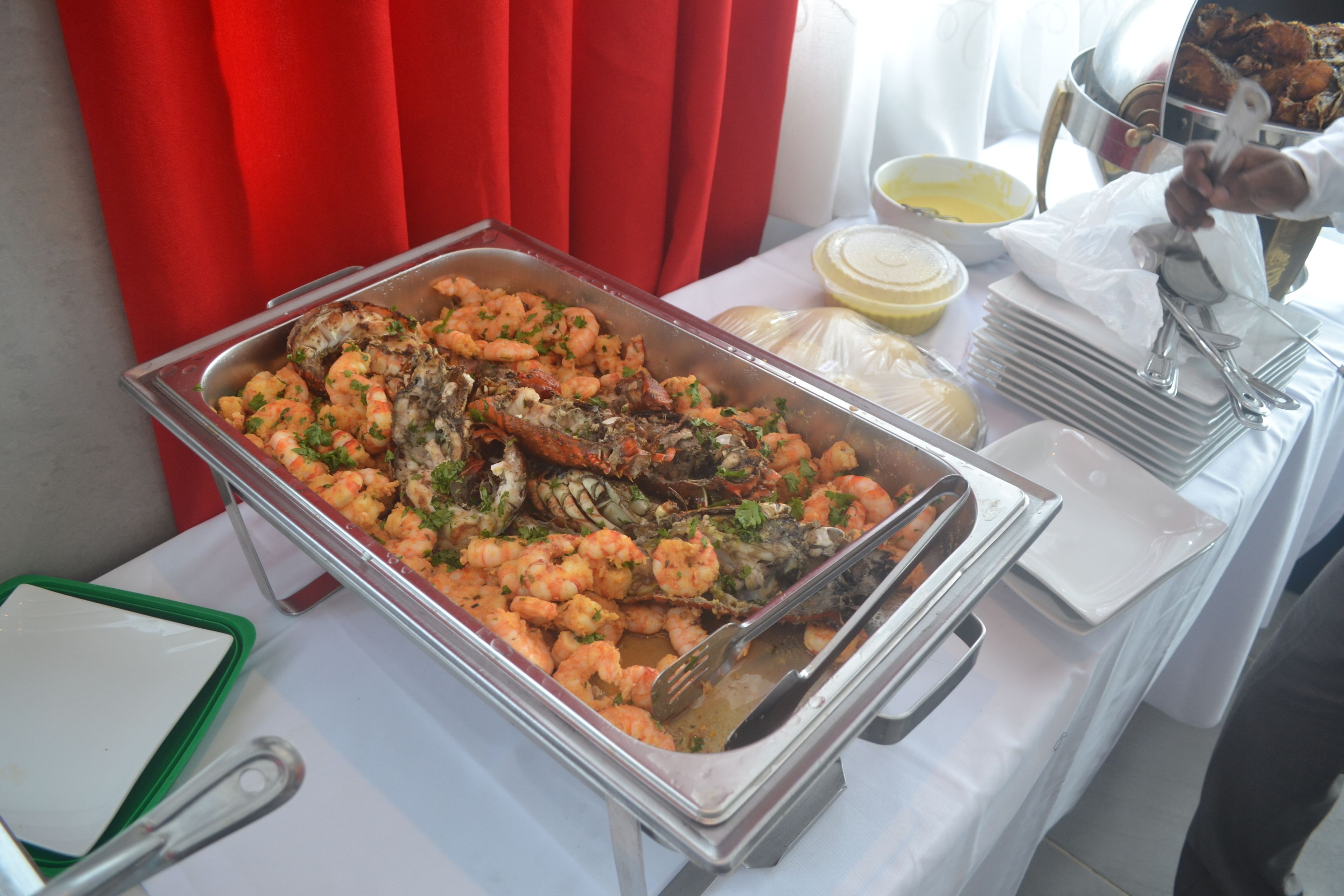 A buffet table with seafood dishes, including shrimp and lobster, and a variety of sauces.