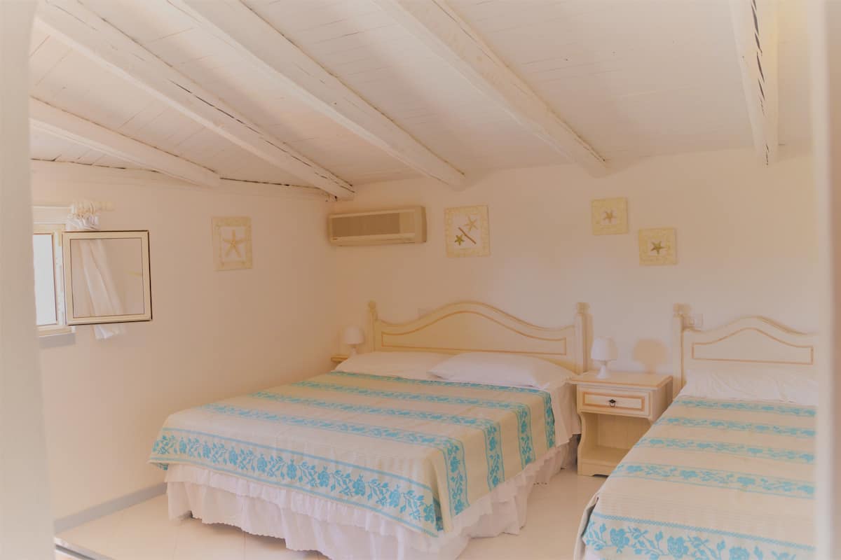 Una camera da letto con due letti, un soffitto in legno e una finestra con tenda.