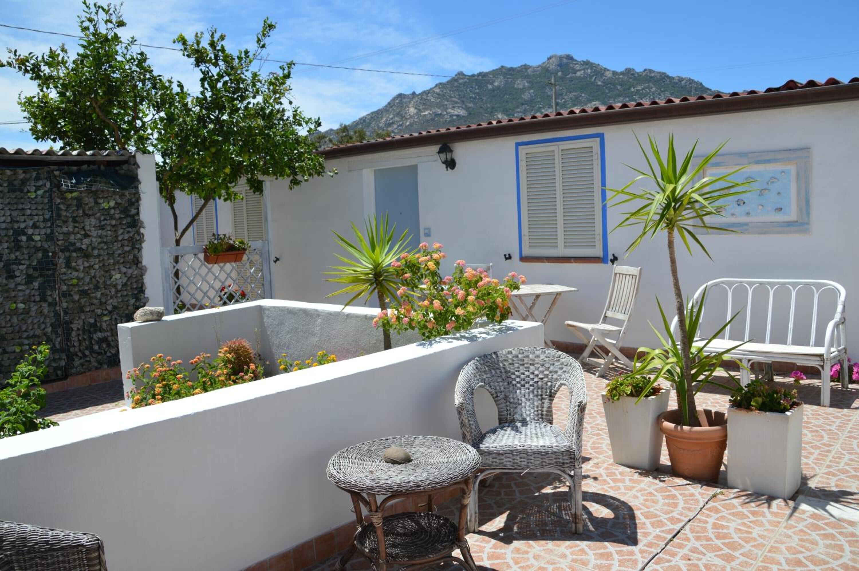 A terrace with wicker furniture, potted plants, and a view of mountains.