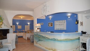 Uma área de recepção com um mural de uma cena de praia, um leme e um relógio na parede.