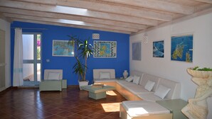 Sala de estar com parede azul, sofá branco, mesa de centro e planta em vaso.