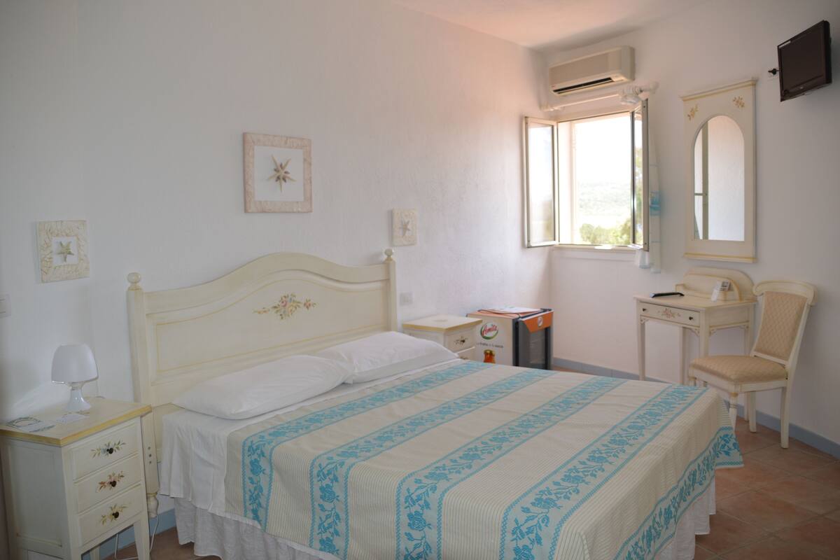 Una camera da letto con un letto, un comodino, una sedia e una finestra vista.