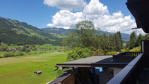 Vista panorámica desde un balcón sobre un valle verde con montañas al fondo.
