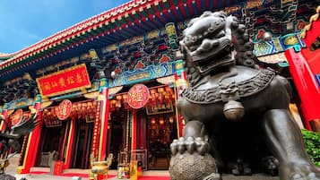A traditional Chinese building with ornate decorations, a lion statue, and a red sign with Chinese characters.