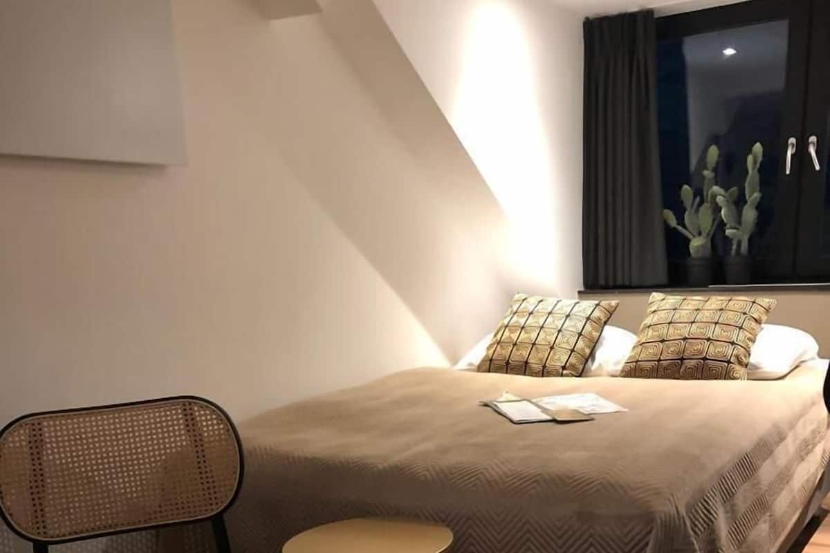 Une chambre à coucher moderne avec un lit, une chaise et une petite table ronde.