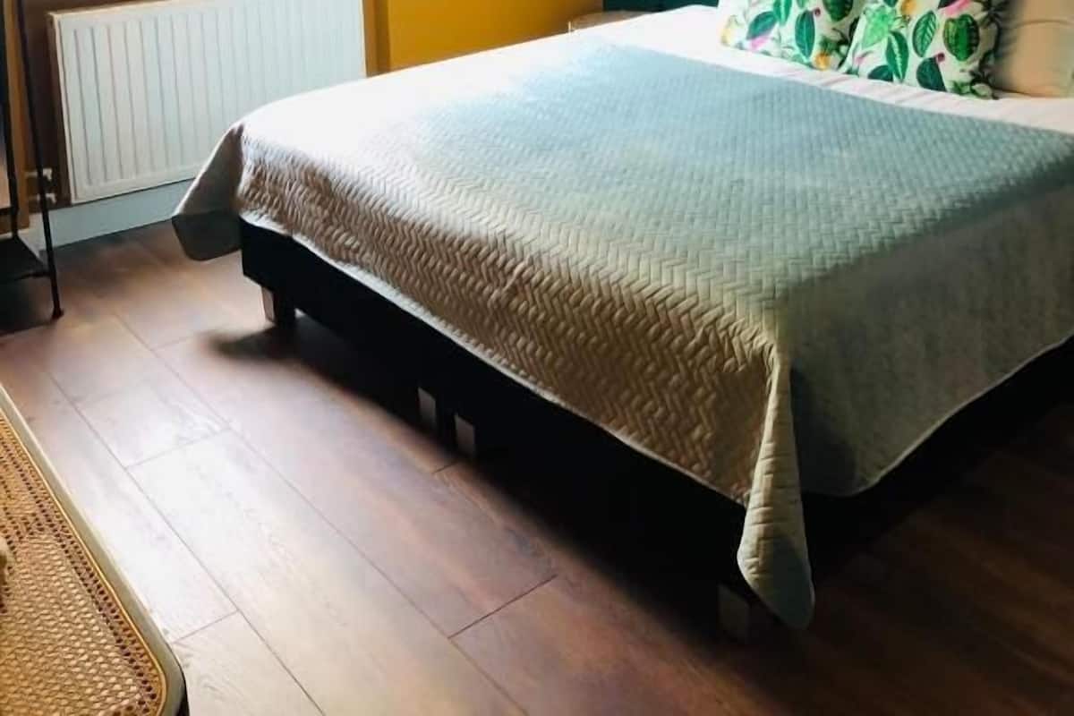 Une chambre à coucher avec un lit, une fenêtre avec des stores, un radiateur et un globe terrestre fixé au mur.