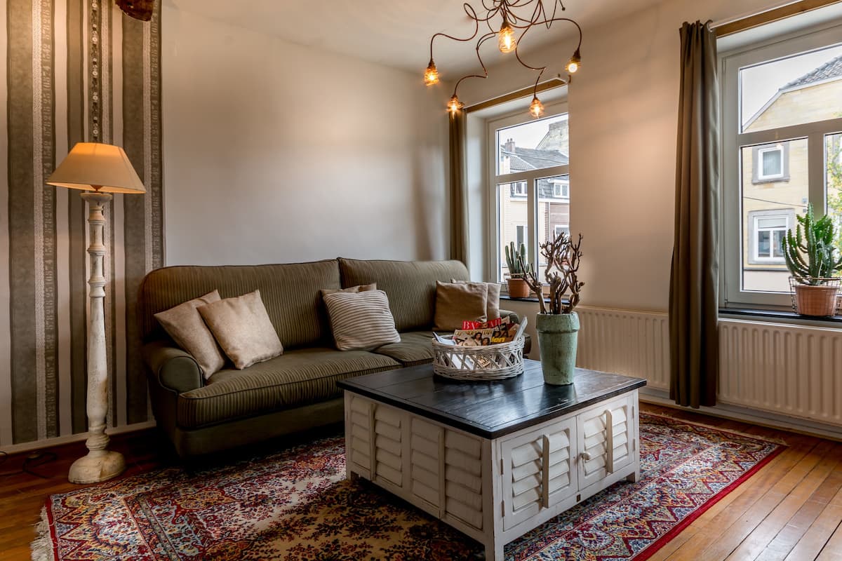 Un salon confortable avec un canapé, une table basse, une lampe sur pied et une fenêtre avec des rideaux.