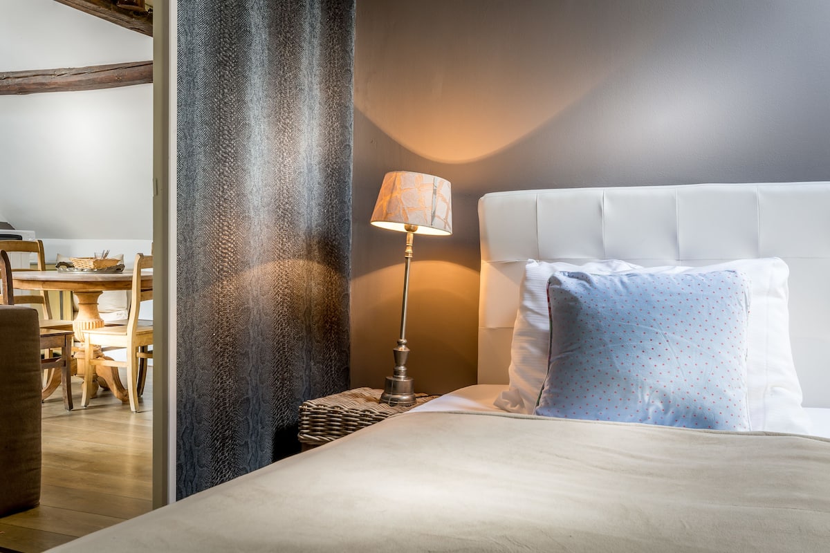 Une chambre à coucher bien rangée, avec un lit, une lampe de chevet, une table de chevet et une chaise.