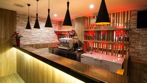 A modern bar area with a stone wall, wooden counter, and black pendant lights. - Marrakesh Inn (Jakarta)
