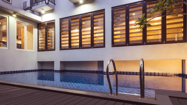 A swimming pool with a tiled deck, wooden railings, and a balcony with glass doors. - Marrakesh Inn (Jakarta)