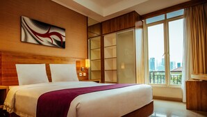 A hotel room with a large bed, a city view, a sliding door closet, and a modern abstract painting on the wall. - Marrakesh Inn (Jakarta)