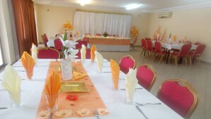 A banquet hall with tables set for a meal, featuring a central buffet area and red chairs. - Hotel Aladje (Abidjan)