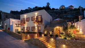 Un edificio con pareti in pietra e una scala che conduce a un balcone, immerso nel verde e sotto un cielo notturno sereno.