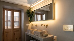 Un bagno moderno con uno specchio grande, due lavabi, una porta in legno e una pianta al muro.