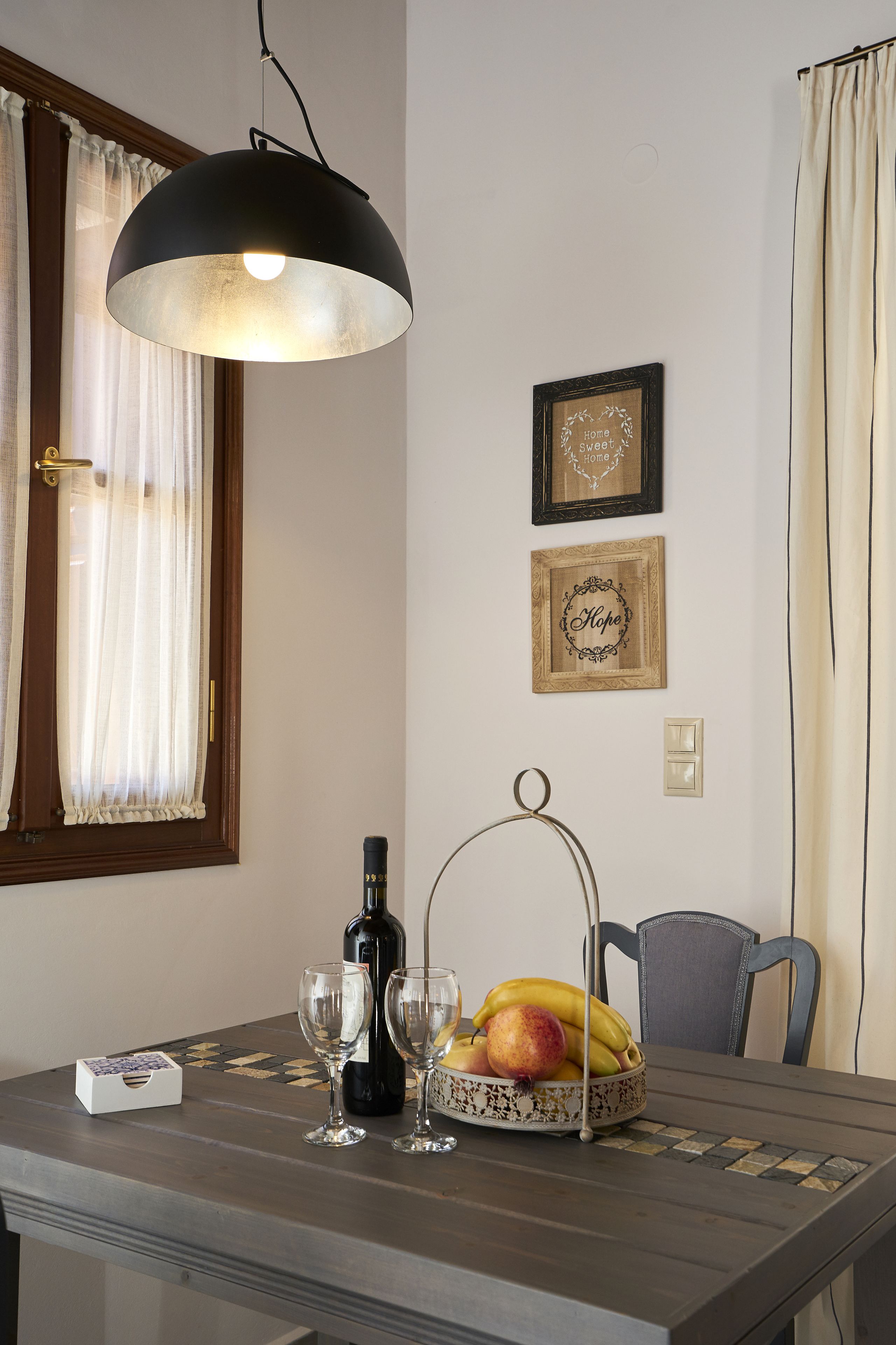 A dining table with a wine bottle, glasses, and a fruit bowl.