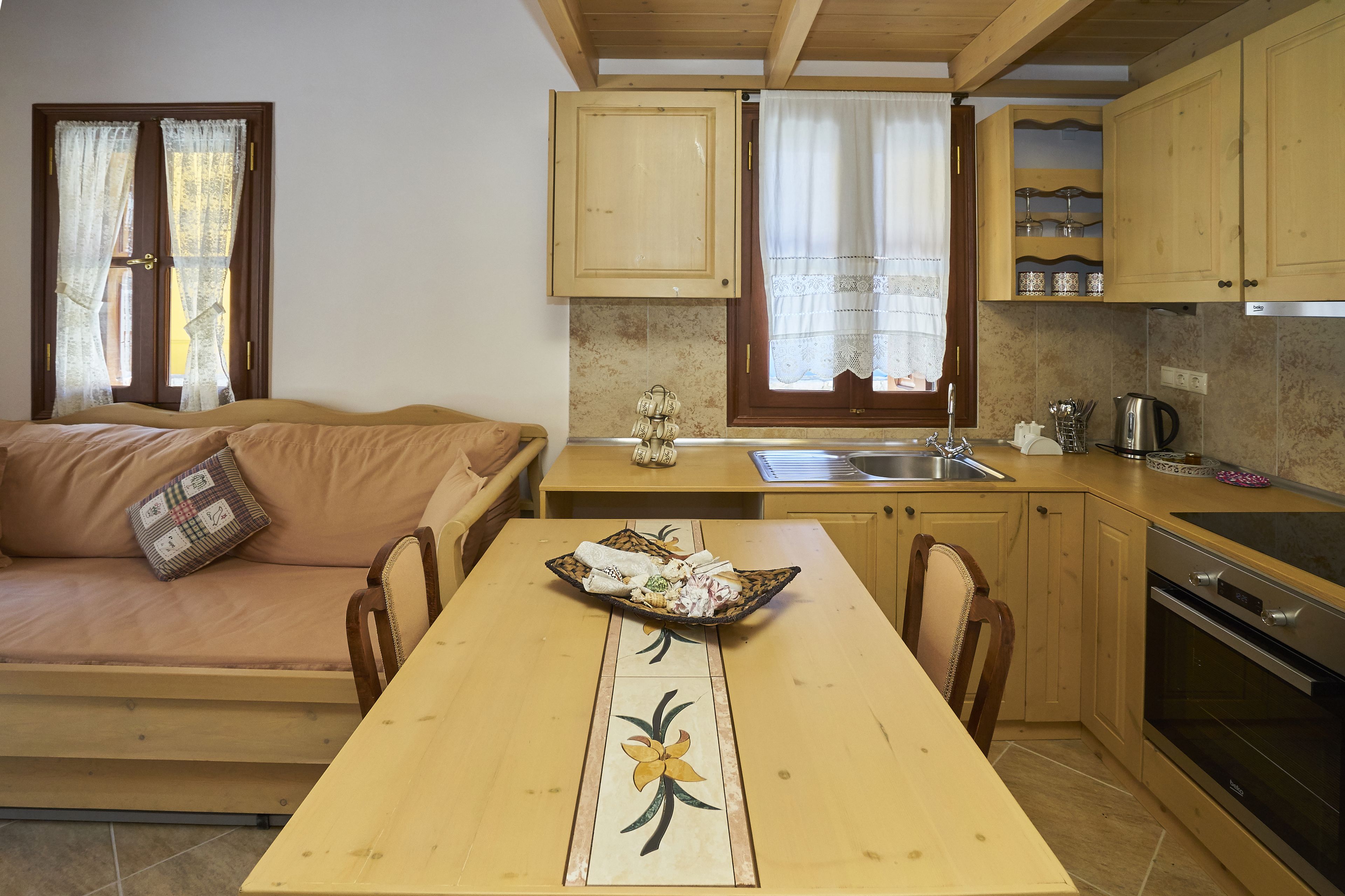 A compact kitchen with a dining table, a sofa, and a built-in oven.