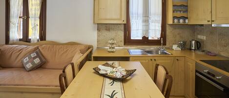 A compact kitchen with a dining table, a sofa, and a built-in oven.
