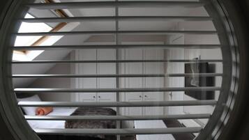 A room with a skylight, white walls, and a bed with a gray headboard.