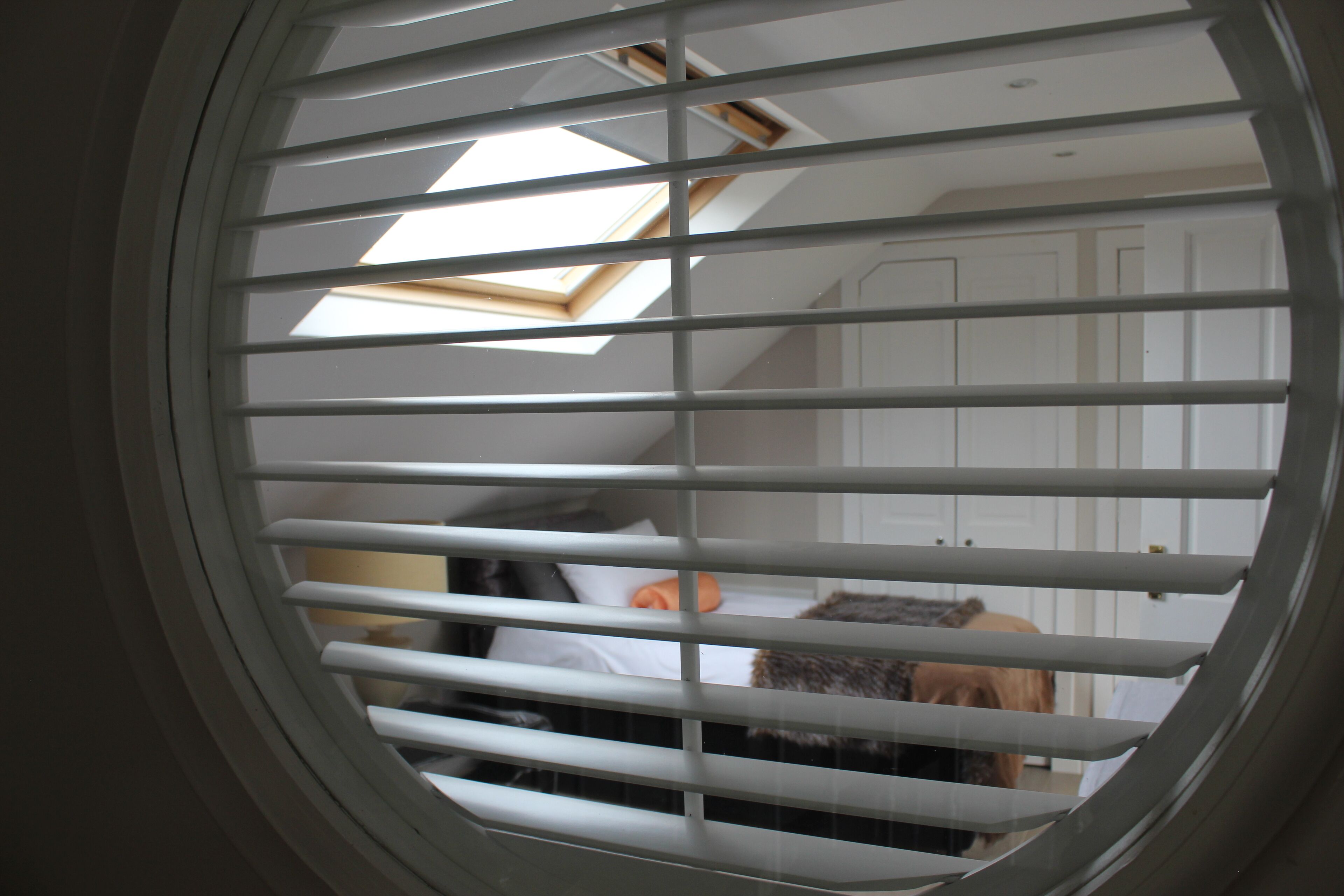 Una habitación con tragaluz y ventana con persianas.