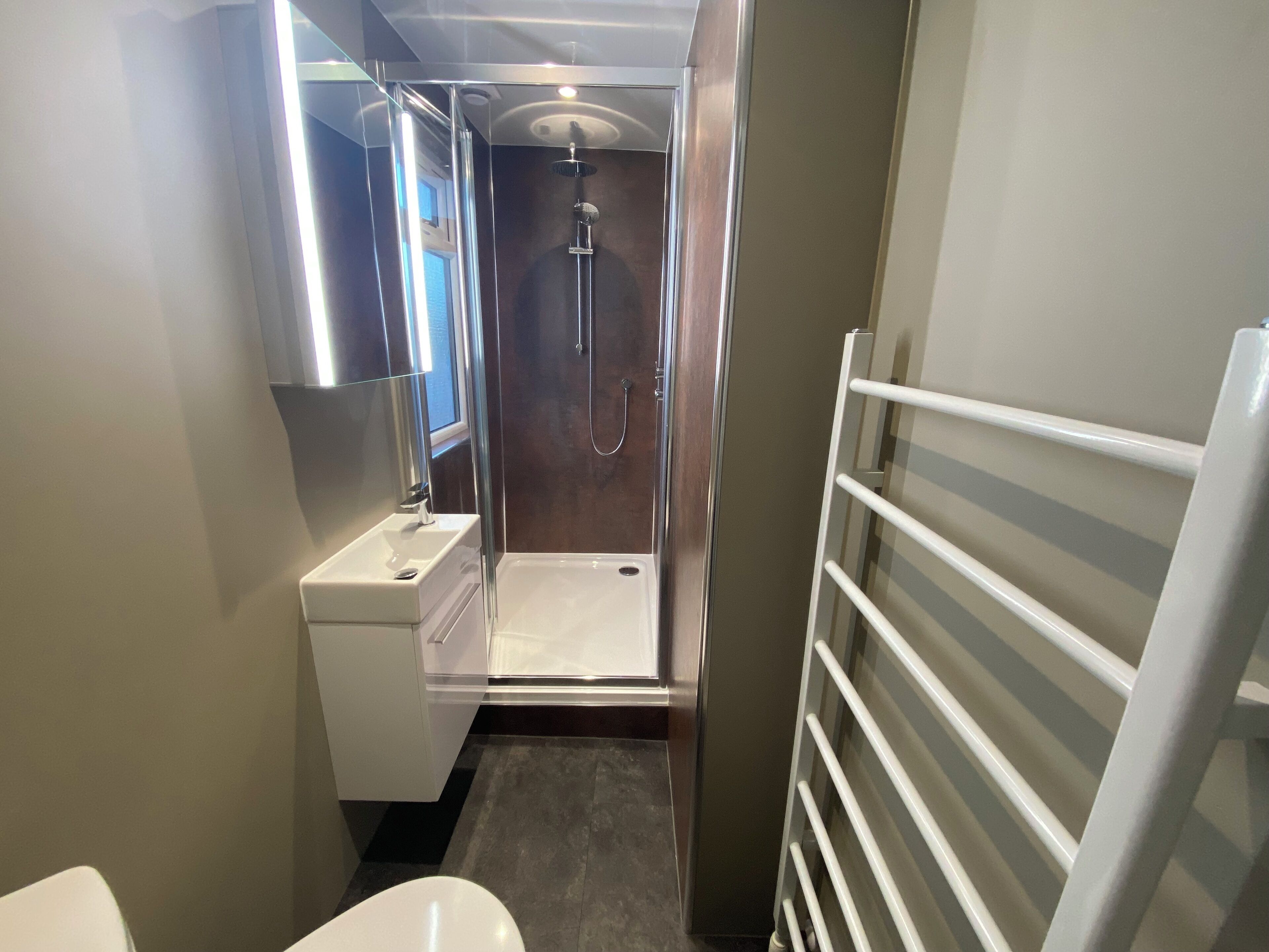 A compact bathroom with a shower, a sink, and a toilet.