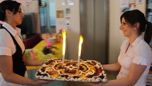 A person holding a cake with lit candles. - Hotel Madrid (Cattolica)
