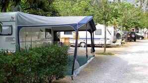 En campingplads med en campingvogn under et tag og et telt.