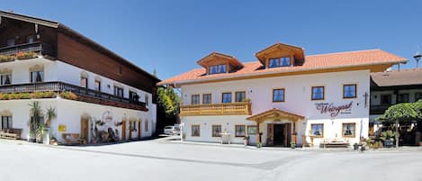 A traditional European building with a white facade, wooden balconies, and a sign indicating it is a restaurant.