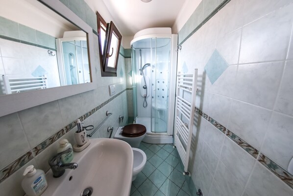 Un baño con lavamanos, inodoro, ducha y espejo.