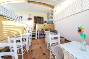 A sunlit patio with white furniture, a glass table, and a flower vase. - Dimore Sonore (Gallipoli)