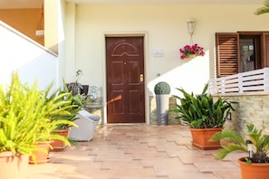 A tiled entrance with a brown door, potted plants, and a white fence. - Dimore Sonore (Gallipoli)