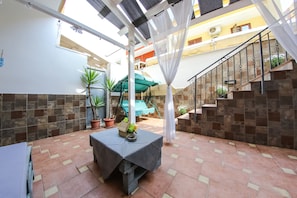 A covered patio area with a table, potted plants, and a staircase. - Dimore Sonore (Gallipoli)